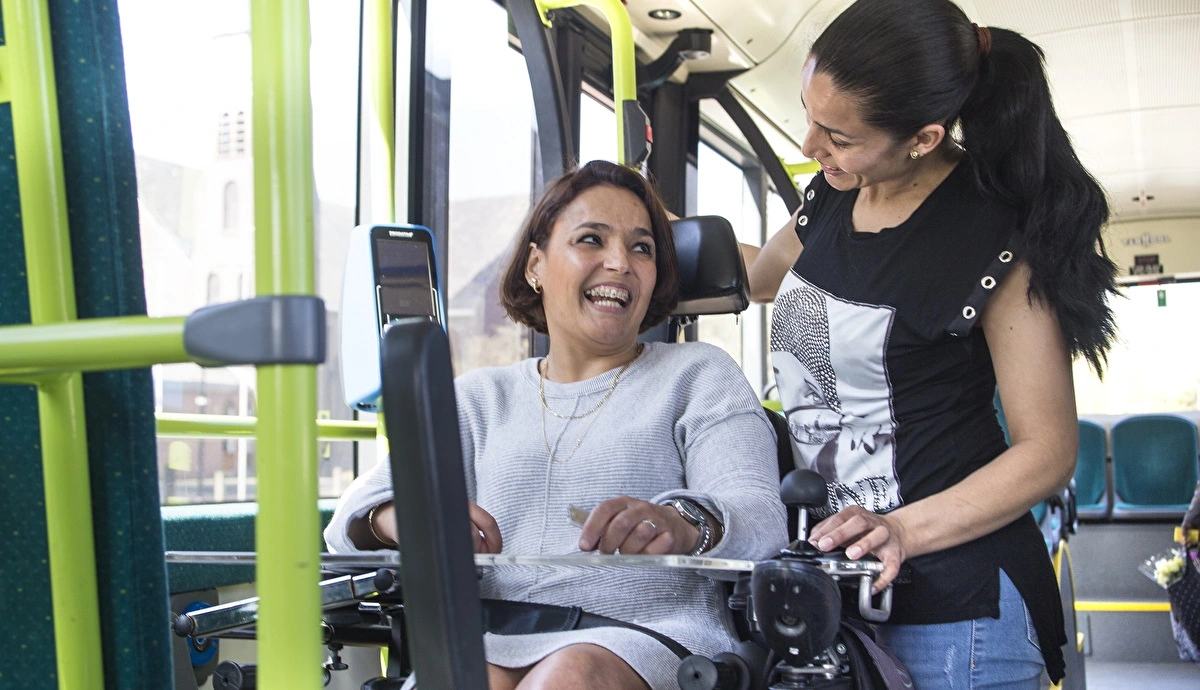 Jongere vrouw in rolstoel in streekbus met andere jonge vrouw 